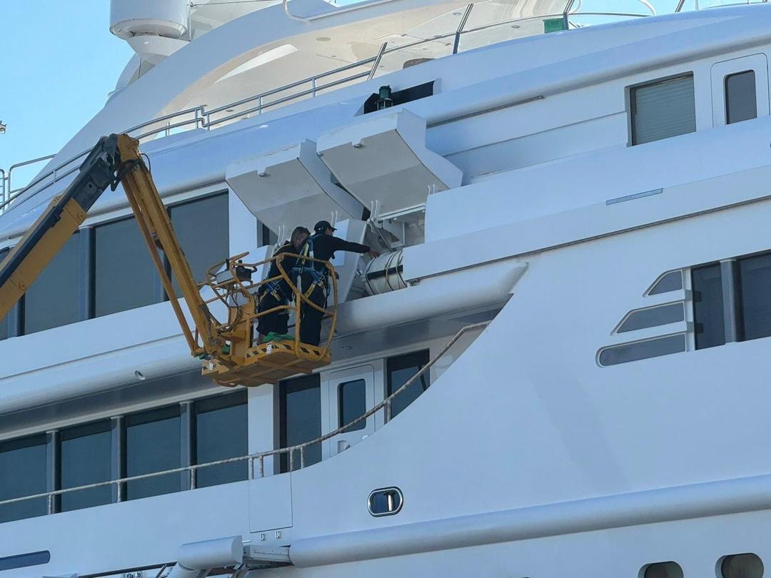 Technicians working on a superyacht from a boom lift